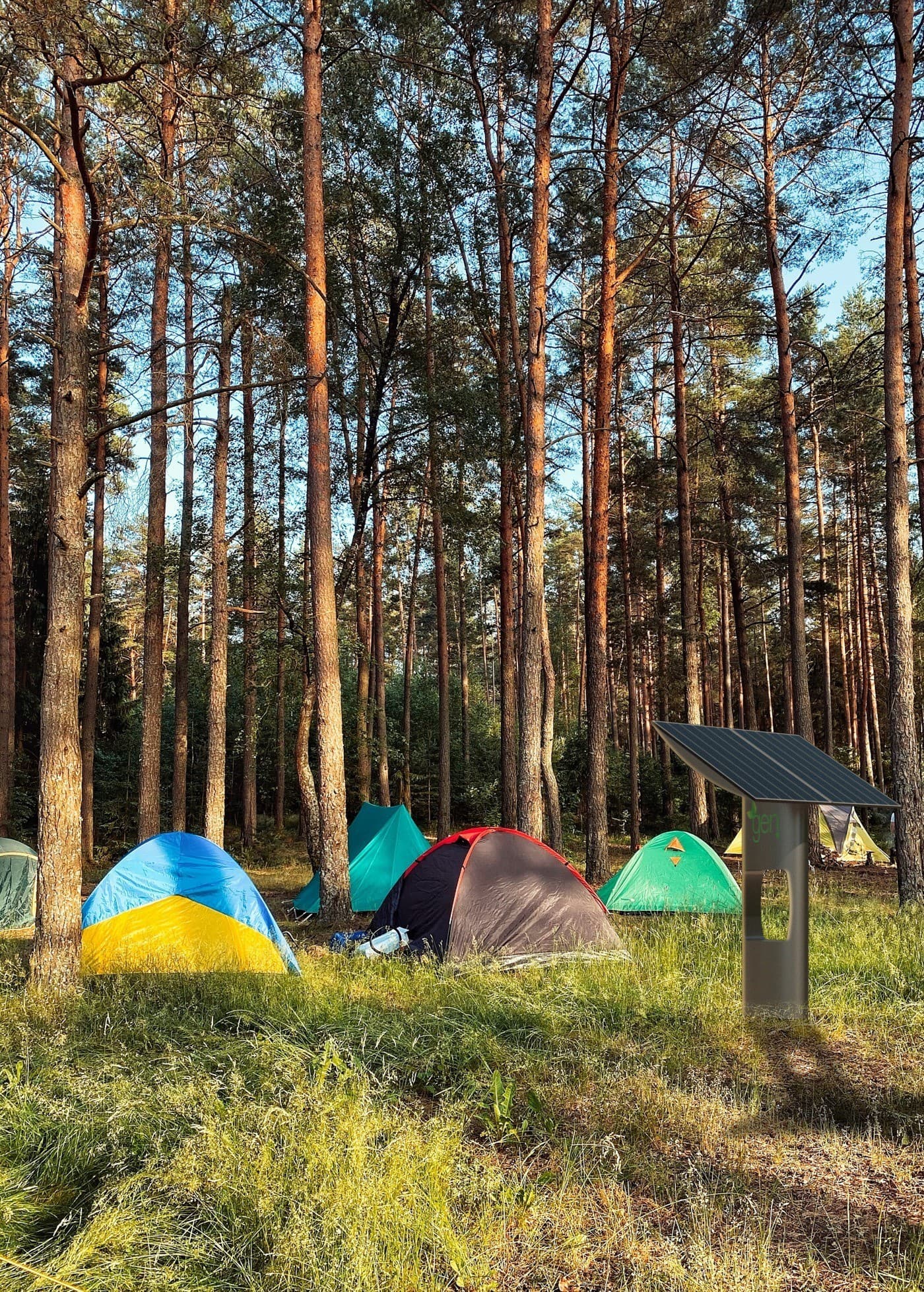 Microgen photovoltaic shelter at a campsite in the woods, next to the tents