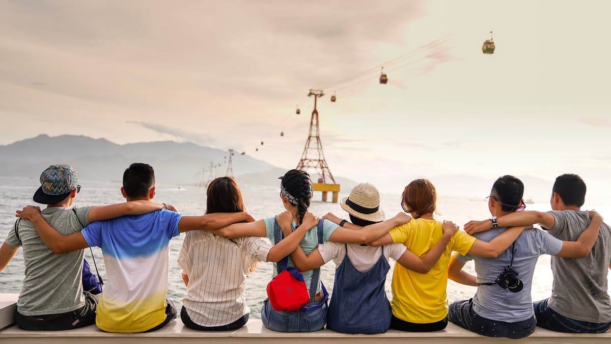 Un gruppo di persone abbracciate di spalle guarda il mare